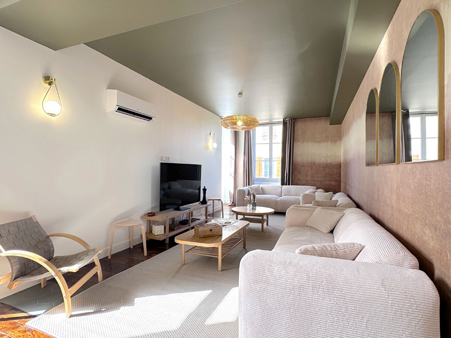 Un salon joliment décoré avec trois beau et grand canapé, un plafond peint en vert et des miroir pour agrandir la pièce